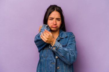 Mor arka planda izole edilmiş genç İspanyol kadın stresten dolayı boynu ağrıyor, masaj yapıyor ve elle dokunuyor..