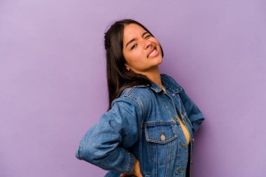 Mor arka planda izole edilmiş, sırt ağrısı çeken genç İspanyol kadın..