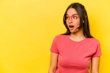Sarı arka planda izole edilmiş genç İspanyol kadın gördüğü bir şey yüzünden şoka uğruyor..