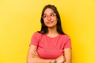 Sarı arka planda izole edilmiş genç İspanyol kadın amaçlarına ve amaçlarına ulaşma hayali kuruyor.