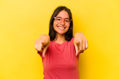Sarı arka planda izole edilmiş genç İspanyol kadın. Önü işaret eden neşeli gülümsemeler..