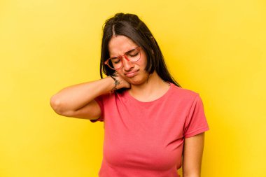 Sarı arka planda izole edilmiş genç bir İspanyol kadın sabit yaşam tarzından dolayı boyun ağrısı çekiyor..