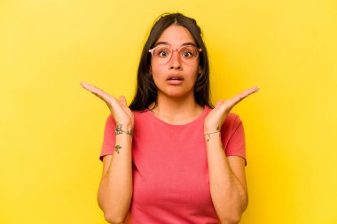 Sarı arka planda izole edilmiş genç İspanyol kadın şaşırdı ve şok oldu..