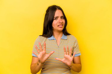 Sarı arka planda izole edilmiş genç İspanyol kadın tiksinti belirtisi gösteren birini reddediyor..