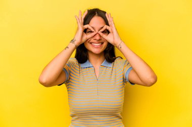 Sarı arka planda izole edilmiş genç İspanyol kadın gözlerinde iyi işaretler gösteriyor.