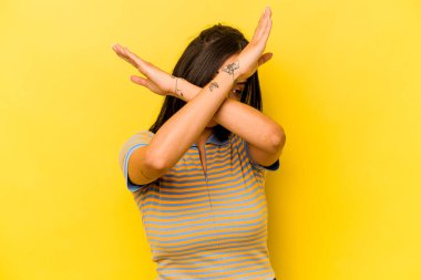 Sarı arka planda izole edilmiş genç İspanyol kadın iki kolu çapraz tutuyor, inkar kavramı.