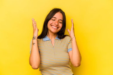 Sarı arka planda izole edilmiş genç İspanyol kadın neşeli bir şekilde gülüyor. Mutluluk kavramı.