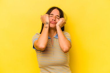 Sarı arka planda izole edilmiş genç İspanyol kadın ağlıyor, bir şeyden memnun değil, acı ve kafa karışıklığı konsepti..