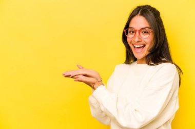 Sarı arka planda izole edilmiş genç İspanyol bir kadın. Elinde palmiyesinde bir kopya alanı var..