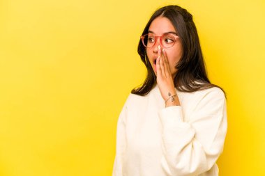 Sarı arka planda izole edilmiş genç İspanyol kadın gördüğü bir şey yüzünden şoka uğruyor..