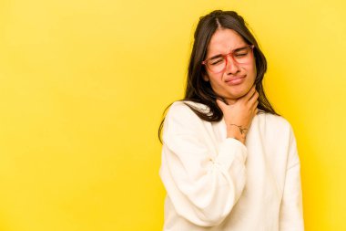 Genç İspanyol kadın sarı arka planda izole edilmiş kafasının arkasına dokunuyor, düşünüyor ve bir seçim yapıyor..
