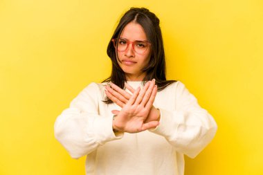 Sarı arka planda izole edilmiş genç İspanyol kadın elini uzatmış, dur işareti göstererek seni engelliyor..