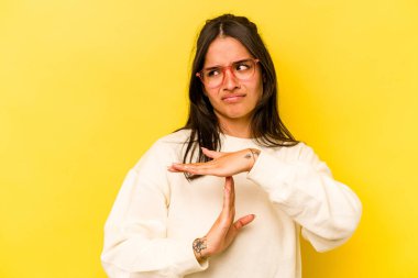 Sarı arka planda izole edilmiş genç İspanyol kadın bir mola hareketi gösteriyor..