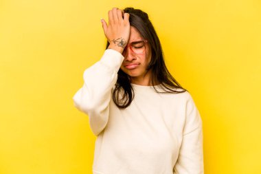 Sarı arka planda izole edilmiş genç İspanyol kadın bir şeyi unutuyor. Alnına avuç içi ile vuruyor ve gözlerini kapıyor..