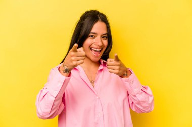 Sarı arka planda izole edilmiş genç İspanyol kadın. Önü işaret eden neşeli gülümsemeler..