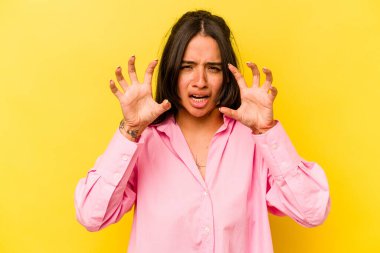 Sarı arka planda izole edilmiş genç İspanyol kadın gergin elleriyle çığlık atıyor..