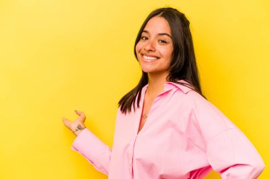 Sarı arka planda izole edilmiş genç İspanyol kadın hoş bir yüz ifadesi sergiliyor..