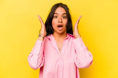 Sarı arka planda izole edilmiş genç İspanyol kadın şaşırdı ve şok oldu..