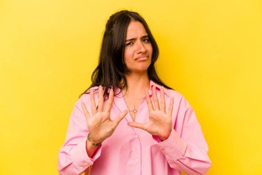 Sarı arka planda izole edilmiş genç İspanyol kadın tiksinti belirtisi gösteren birini reddediyor..