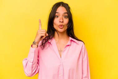 Sarı arka planda izole edilmiş genç İspanyol bir kadının harika bir fikri var, yaratıcılık kavramı..