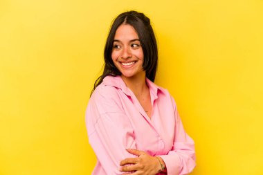 Sarı arka planda yalnız yaşayan genç İspanyol kadın gülüyor ve eğleniyor..