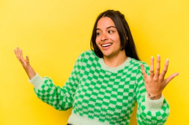 Sarı arka planda izole edilmiş genç İspanyol kadın neşeli bir şekilde gülüyor. Mutluluk kavramı.