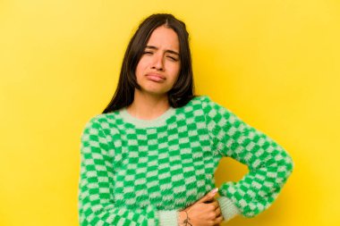 Sarı arka planda karaciğer ağrısı çeken, karnı ağrıyan genç bir İspanyol kadın..