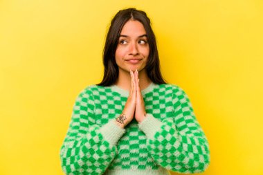 Genç İspanyol kadın sarı arka planda izole edilmiş dua ediyor, bağlılık gösteriyor, dindar biri ilahi ilham arıyor..