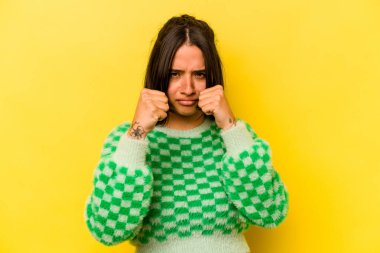 Sarı arka planda izole edilmiş genç İspanyol kadın bir tartışma yüzünden yumruk, öfke, kavga ve boks atıyor..