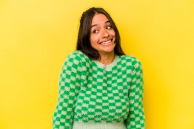 Sarı arka planda izole edilmiş genç İspanyol kadın gülüyor ve gözlerini kapıyor, rahatlamış ve mutlu hissediyor..