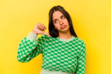 Sarı arka planda izole edilmiş genç İspanyol kadın hoşlanmadığı bir hareket gösteriyor. Anlaşmazlık konsepti.