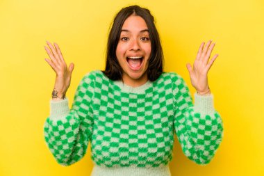 Sarı arka planda izole edilmiş genç İspanyol kadın hoş bir sürprizle karşılaşıyor, heyecanlı ve el kaldırıyor..