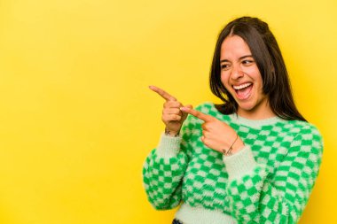 Sarı arka planda izole edilmiş genç İspanyol kadın başparmak uzakta, gülüyor ve kaygısız..