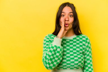 Sarı arka planda izole edilmiş genç İspanyol kadın gizli bir sıcak fren haberi veriyor ve yan bakıyor.