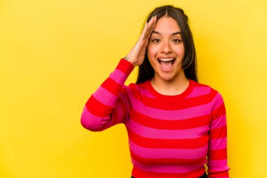 Sarı arka planda izole edilmiş genç İspanyol kadın yüksek sesle bağırıyor, gözleri açık ve elleri gergin tutuyor..