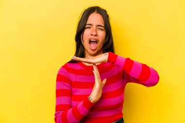 Sarı arka planda izole edilmiş genç İspanyol kadın bir mola hareketi gösteriyor..