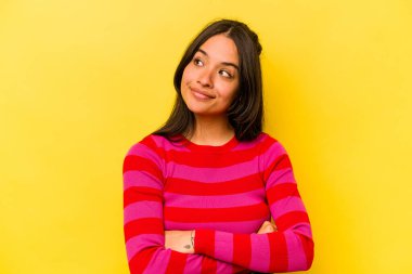 Sarı arka planda izole edilmiş genç İspanyol kadın amaçlarına ve amaçlarına ulaşma hayali kuruyor.