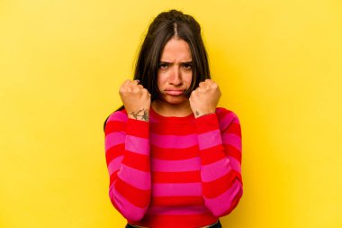 Sarı arka planda izole edilmiş genç İspanyol kadın gergin elleriyle çığlık atıyor..