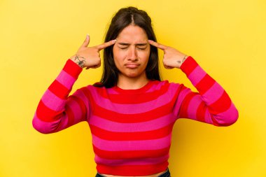 Sarı arka planda izole edilmiş genç İspanyol kadın bir işe odaklanmış, işaret parmaklarını işaret ediyor..