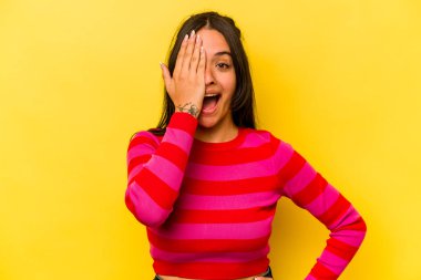 Sarı arka planda izole edilmiş genç İspanyol kadın yüzünün yarısını palmiye ile örterek eğleniyor..