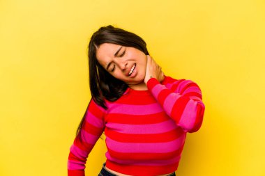 Sarı arka planda izole edilmiş genç bir İspanyol kadın sabit yaşam tarzından dolayı boyun ağrısı çekiyor..