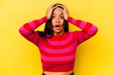 Sarı arka planda izole edilmiş genç İspanyol kadın şaşırdı ve şok oldu..