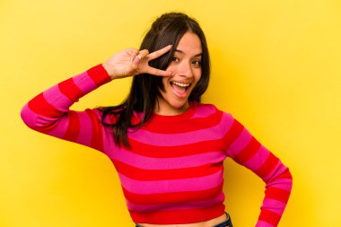 Sarı arka planda yalnız yaşayan genç İspanyol kadın dans ediyor ve eğleniyor..