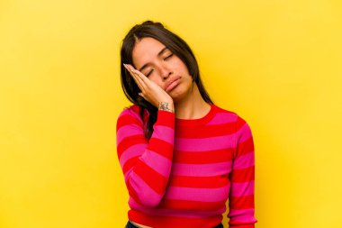 Sarı arka planda izole edilmiş genç İspanyol kadın. Sıkılmış, yorgun ve dinlenmeye ihtiyacı var..