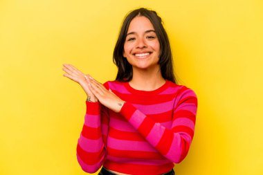 Sarı arka planda izole edilmiş genç İspanyol kadın enerjik ve rahat hissediyor, ellerini ovuşturuyor..