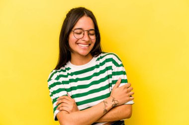 Sarı arka planda yalnız yaşayan genç İspanyol kadın gülüyor ve eğleniyor..