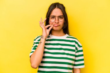 Sarı arka planda izole edilmiş genç İspanyol kadın parmakları dudaklarında bir sır saklıyor..