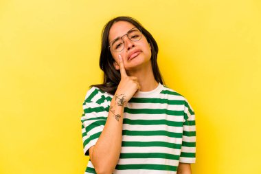 Sarı arka planda izole edilmiş genç İspanyol kadın ağlıyor, bir şeyden memnun değil, acı ve kafa karışıklığı konsepti..