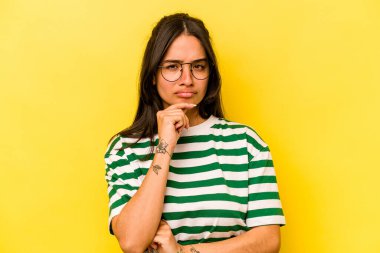 Genç İspanyol kadın sarı arka planda izole edilmiş düşünüyor, bakıyor, yansıtıyor, düşünüyor, hayal kuruyor..