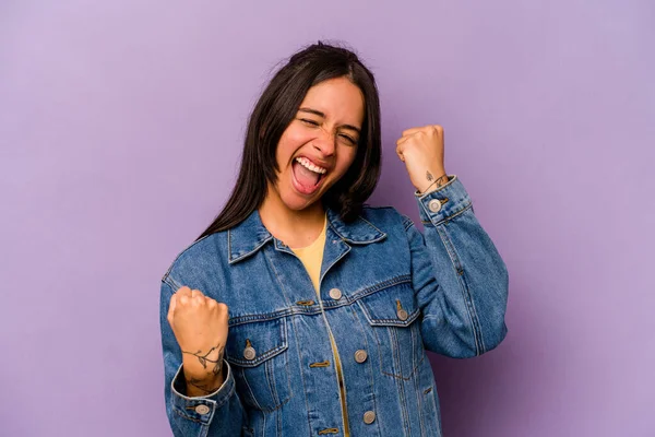 Mor arka planda izole edilmiş genç İspanyol kadın tasasız ve heyecanlı bir şekilde tezahürat yapıyor. Zafer konsepti.